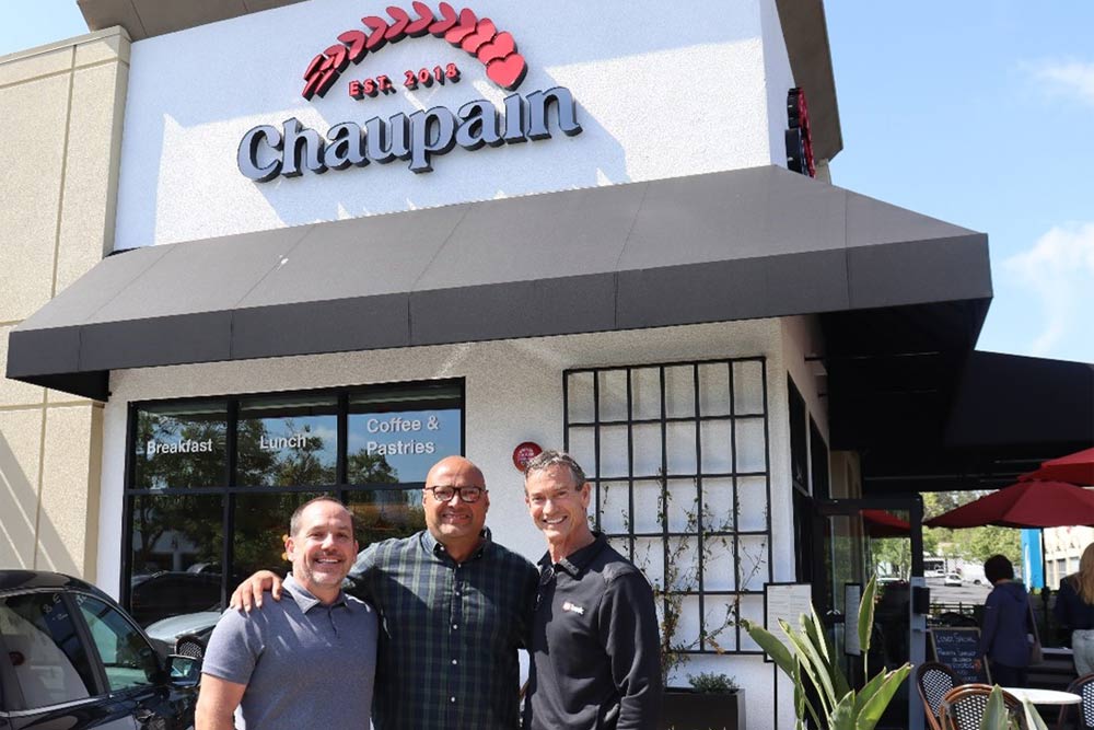 Photo of three men standing in front of a bakery