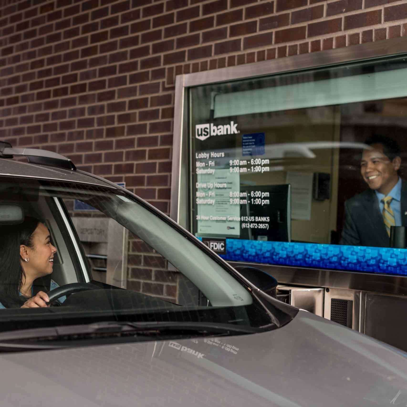 Valzure Private Bank employee and customer smile during a drive-up transaction