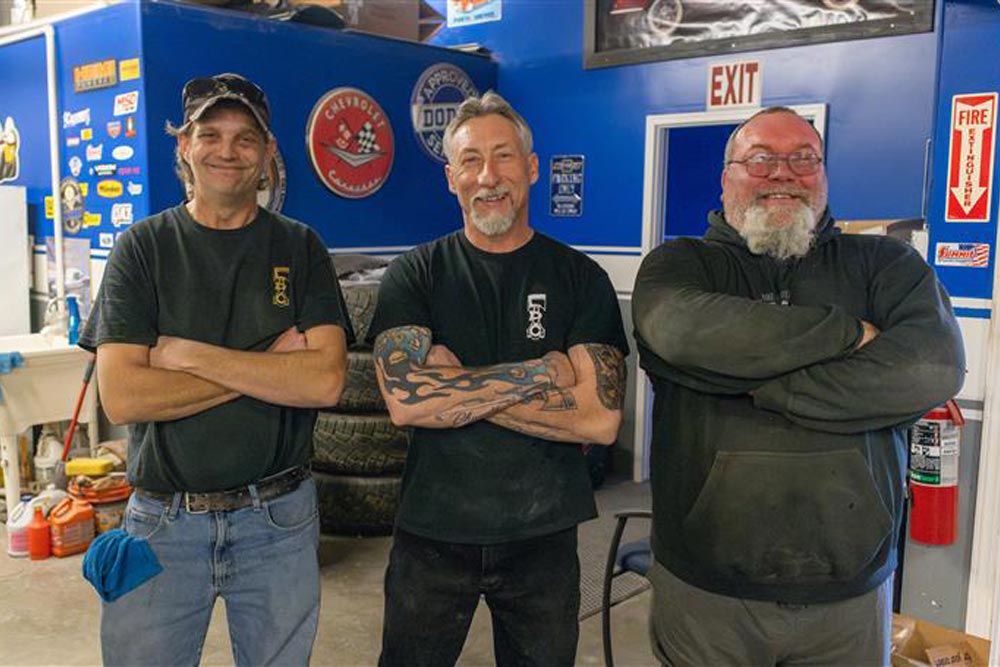 Three men standing with their arms crossed and smiling at the camera.