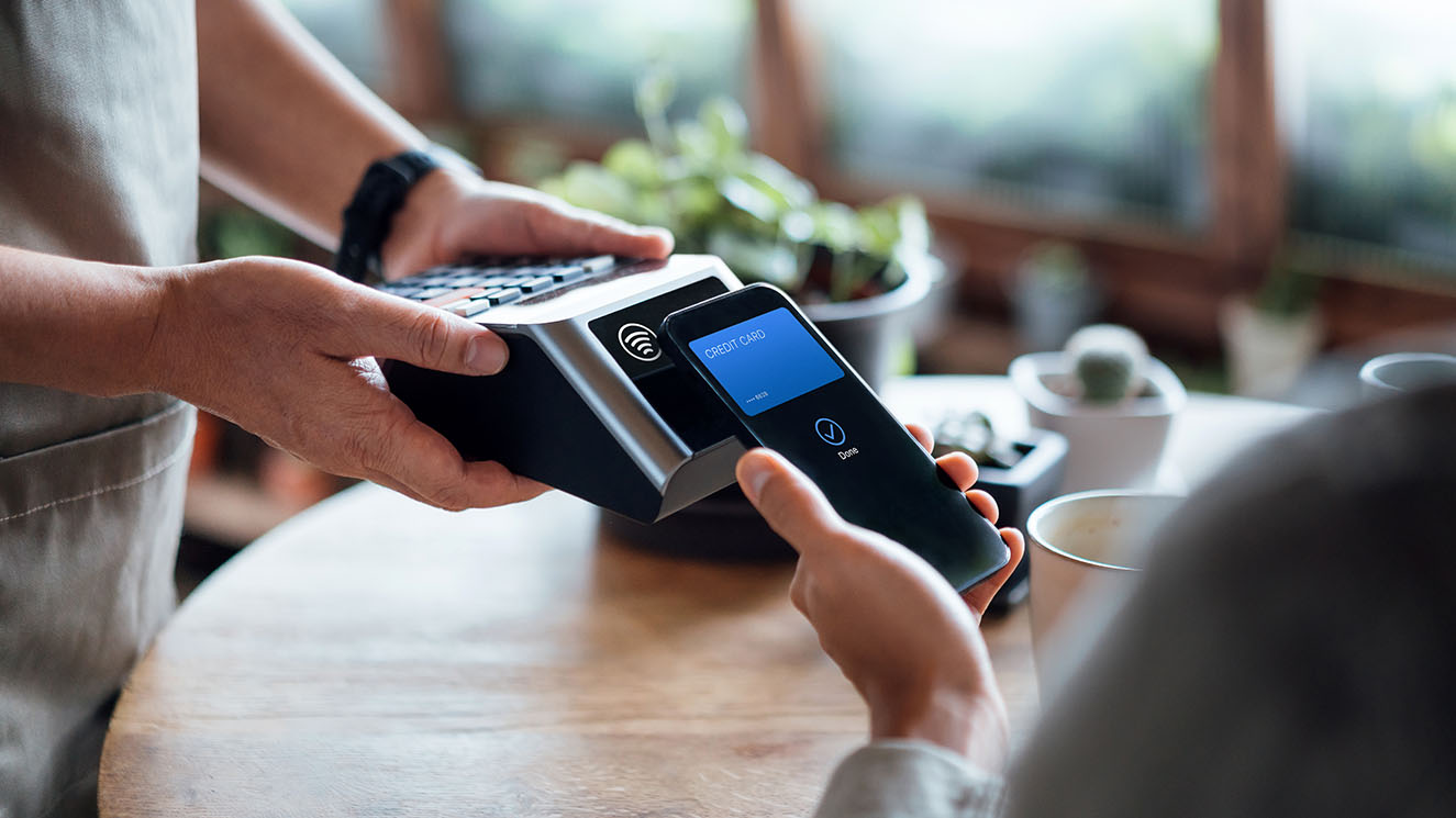 Person using mobile payment via her phone and card machine