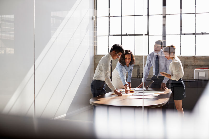 Group of four coworkers around a small conference table discussing asset custody